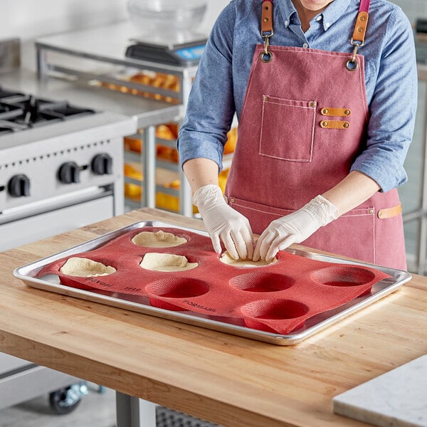 A woman in a pink apron uses a Pavoni Formasil round silicone mold to make pastries.