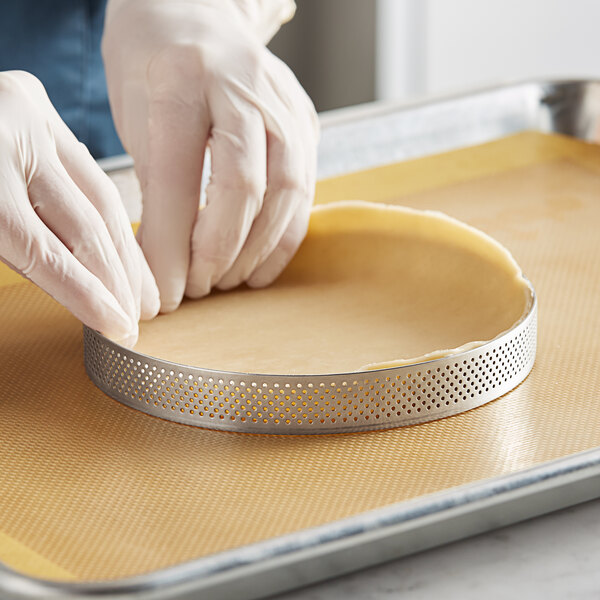 A person in gloves using a Pavoni Progetto Crostate tart ring to cut pie crust.