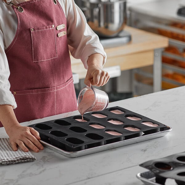 A woman pouring pink liquid into a Pavoni Pavoflex silicone cupcake mold.