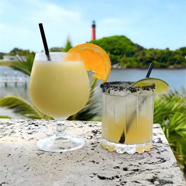 A pair of cocktails on a marble surface, each with a black unwrapped jumbo cocktail straw.