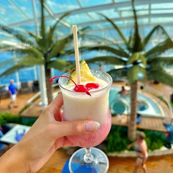 A natural wrapped giant straw in a tropical drink garnished with cherries and pineapple.