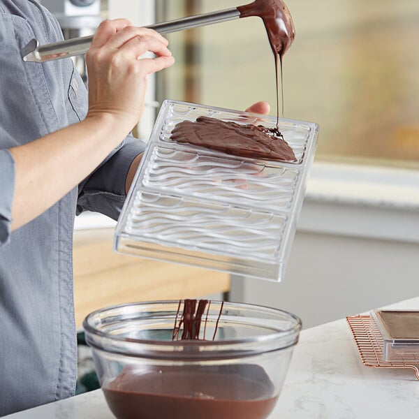 A woman using a Pavoni chocolate bar mold to pour chocolate.