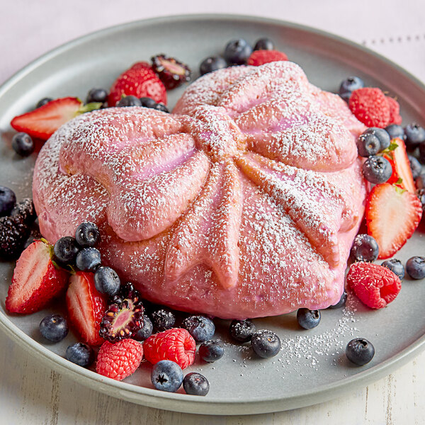 A pink dessert with strawberries and powdered sugar in a Pavoni Pavocake Cadeau silicone baking mold compartment.
