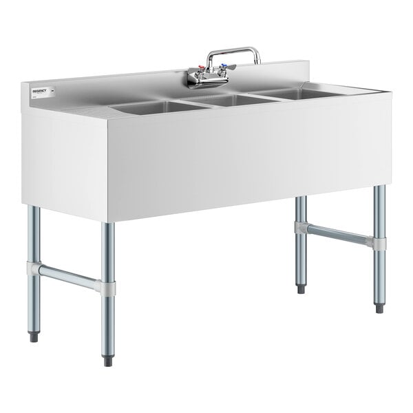 A stainless steel three-compartment sink with a faucet and four metal legs, featuring a backsplash and no visible drainboard on the left side.