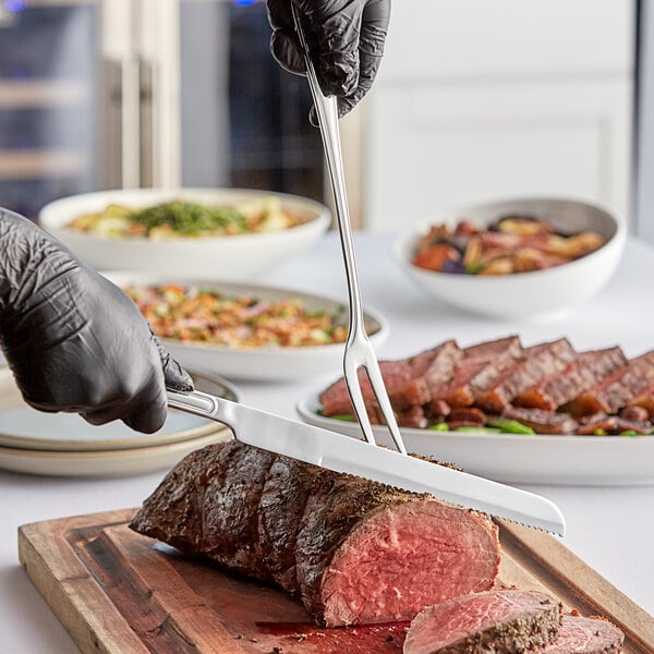 A person using an Acopa Edgeworth stainless steel knife to cut meat on a wooden cutting board.