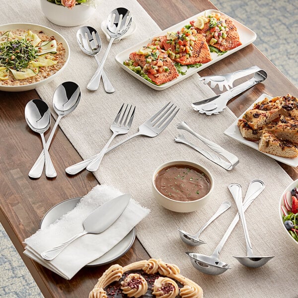 A table with plates of food and Acopa Swirl stainless steel serving forks.