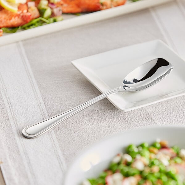 An Acopa Edgeworth stainless steel serving scoop on a plate of food.