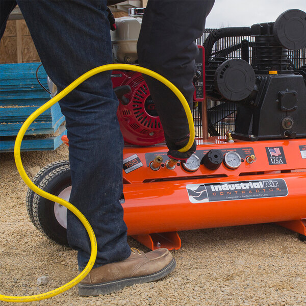 A man using an Industrial Air Contractor wheelbarrow air compressor to fill a tire.
