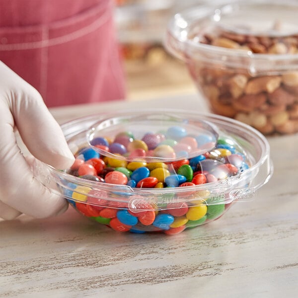 A person holding an Inline Plastics Safe-T-Fresh plastic container filled with colorful candy.