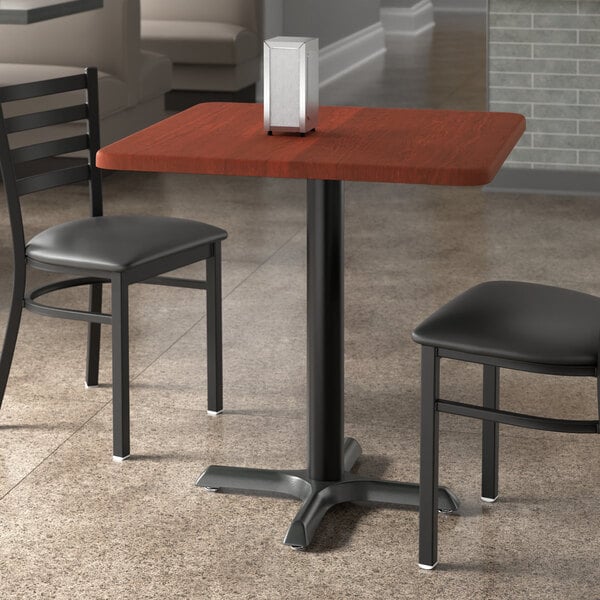 A Lancaster Table & Seating square table with red mahogany finish and two chairs.