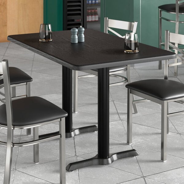 A table with salt and pepper shakers on it and a Lancaster Table & Seating rectangular thermo-formed MDF table top with black wood finish.