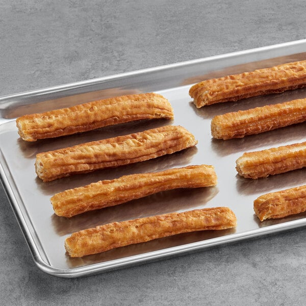 A tray of White Toque fried churros on a gray surface.