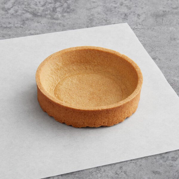 A Pidy sweet butter tart shell on a white paper.