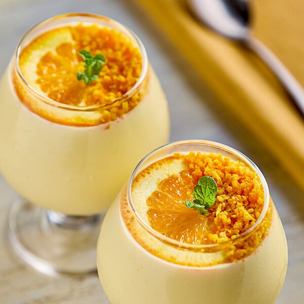 Two glasses of orange juice with orange slices on the rim.