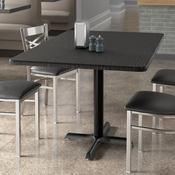 A black Lancaster Table & Seating rectangular table with chairs in a restaurant.