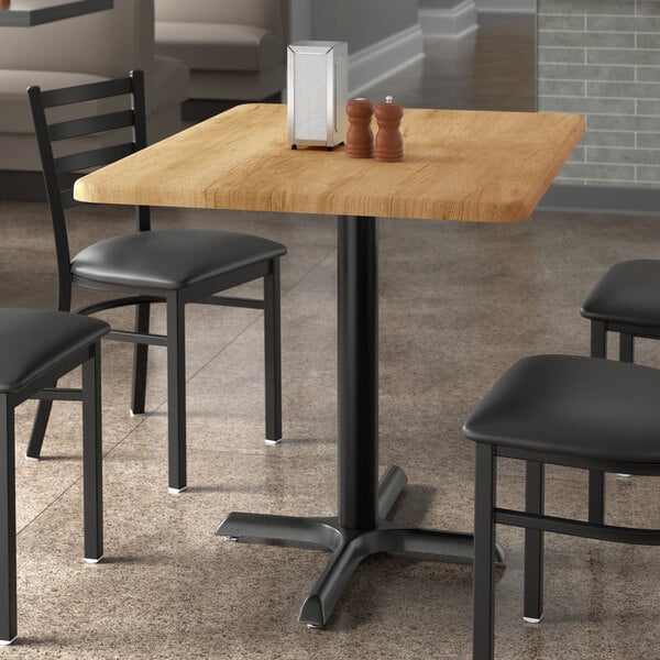 A rectangular wooden table with chairs and salt and pepper shakers.