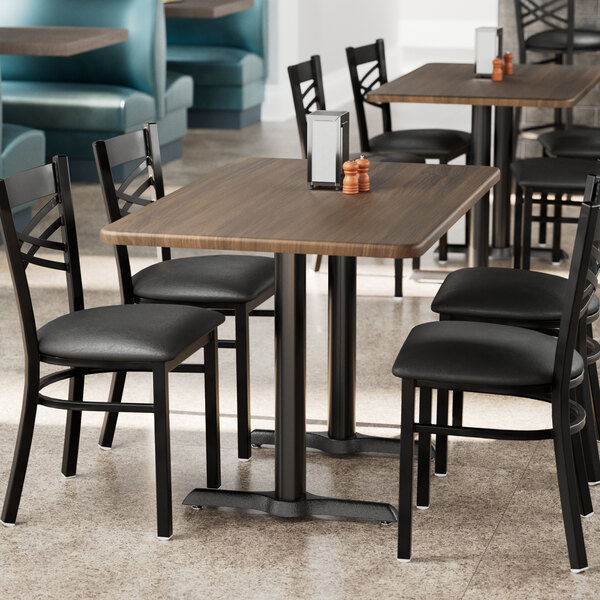 A Lancaster Table & Seating rectangular table with dark walnut finish and chairs in a restaurant.