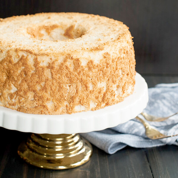 A close up of a Nordic Ware Angel Food cake on a white plate with a gold spoon.