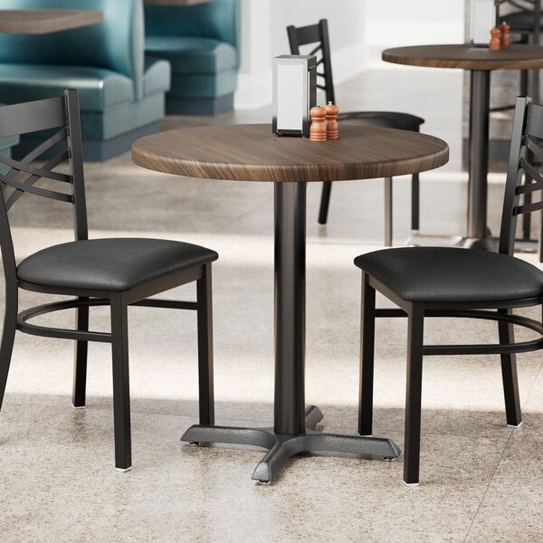 A Lancaster Table & Seating round table with dark walnut finish and chairs in a restaurant dining area.