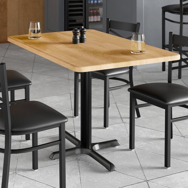 A rectangular table with a maple finish and two glasses on it.