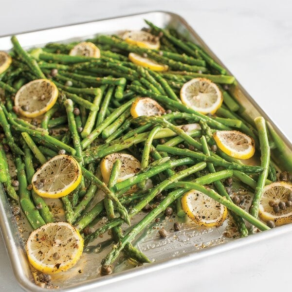 A Nordic Ware sheet pan with asparagus and lemon slices.