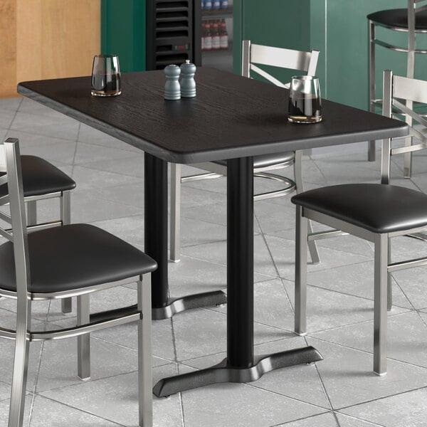 A Lancaster Table & Seating rectangular black table with salt and pepper shakers on it.