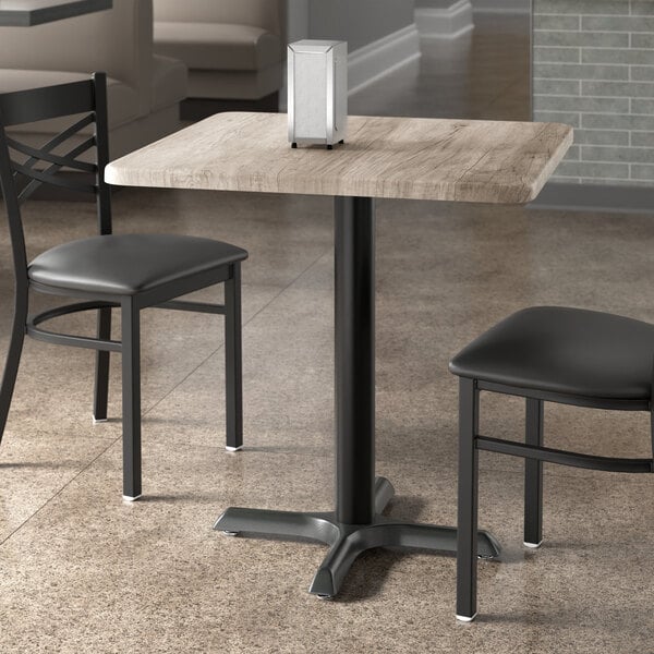 A square standard height table with a gray wood finish and a black metal base.