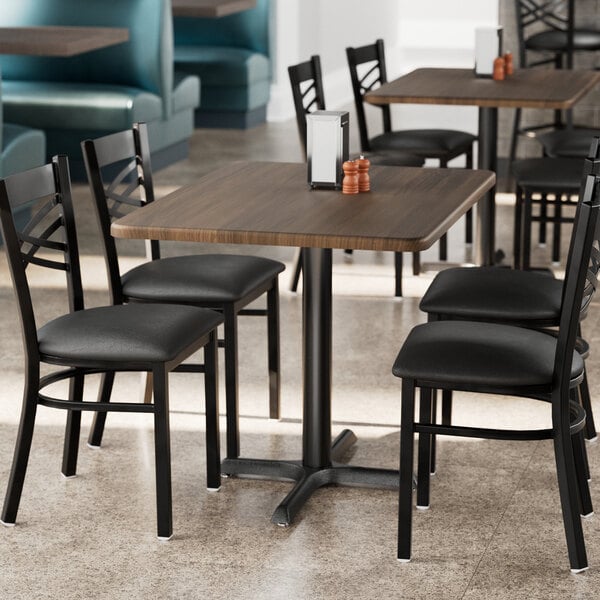 A Lancaster Table & Seating rectangular table with dark walnut finish and chairs in a restaurant.