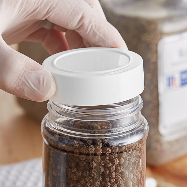 A hand holding a white 63/485 Polypropylene Spice Cap.