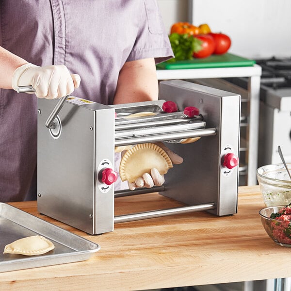 A woman in a purple shirt and gloves using an Estella Manual Turnover Machine to make a pastry.