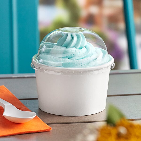 A white Choice paper cup of frozen yogurt with a dome lid on a table.