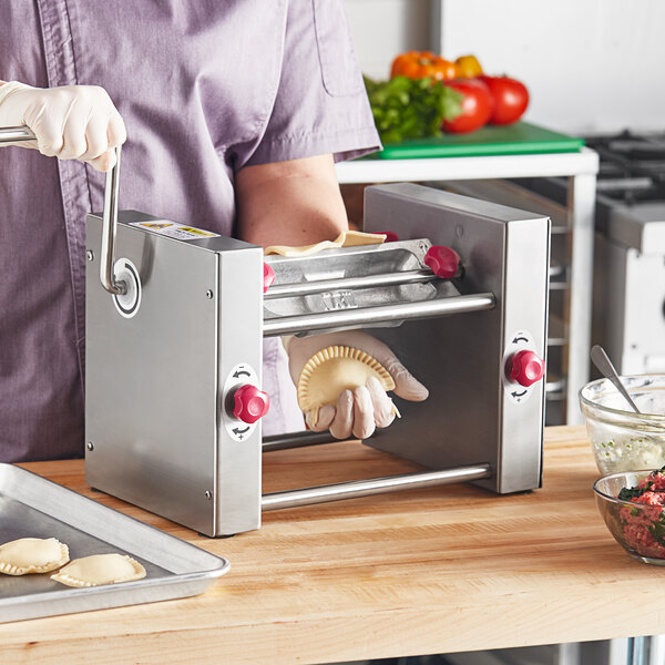 A person using an Estella semi-circle die to make food in a machine.