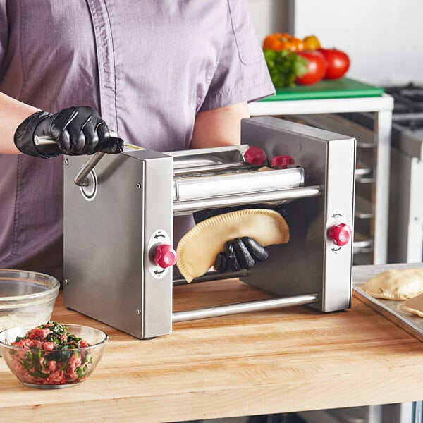 A person in black gloves using the Estella Manual Turnover Machine to make a pastry.