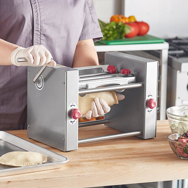 A person using the Estella manual turnover machine to make semi-circle dough pieces.