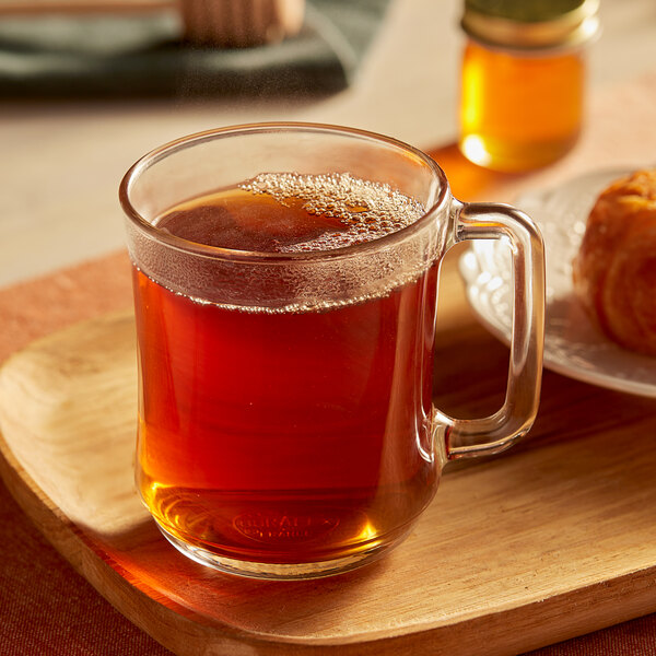 A wooden tray with a glass mug of Bigelow Earl Grey tea next to a pastry.