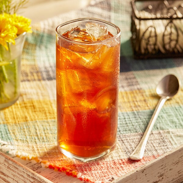 A glass of Lipton Southern sweet iced tea with a spoon on a table.