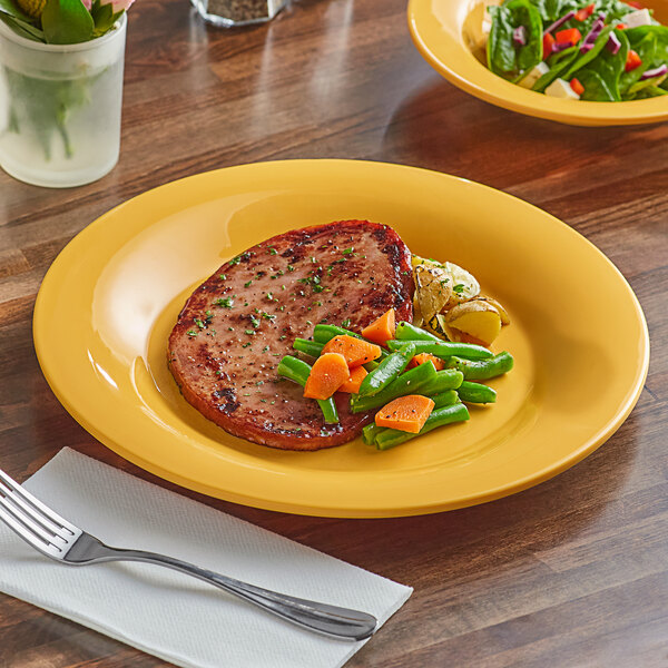 A table set with a yellow Acopa Foundations melamine plate with a meal of salad and vegetables.