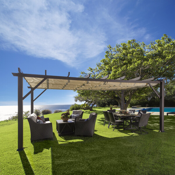 A grassy patio area with Paragon Outdoor Modena pergola and chairs under a mocha canopy.