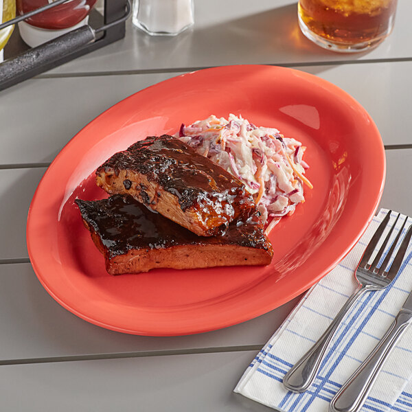 An Acopa orange melamine platter with meat and coleslaw on a table.