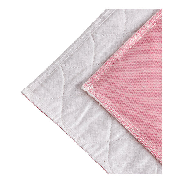 A close up of a pink and white quilt with a white border.