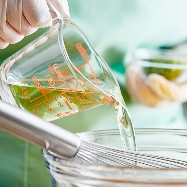 A person pouring Mazola Vegetable Plus! Oil into a measuring cup.