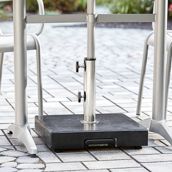 A Lancaster Table & Seating black metal umbrella base on a black surface.
