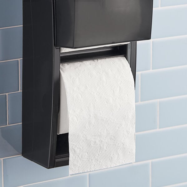 A black toilet paper holder with an individually wrapped white Lavex toilet paper roll.