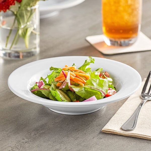 A bowl of salad with carrots and lettuce on a table.