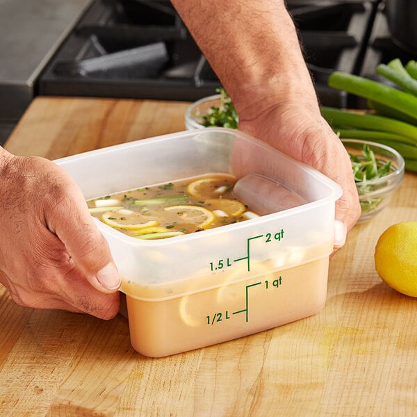 A person holding a Cambro FreshPro food storage container with lemons in it.