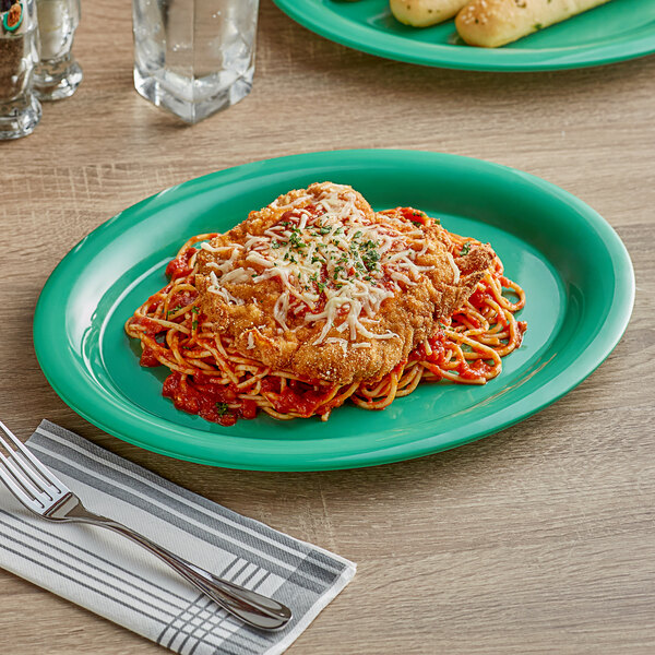 A Acopa Foundations green melamine platter with a plate of spaghetti, meatballs, and cheese on a table.