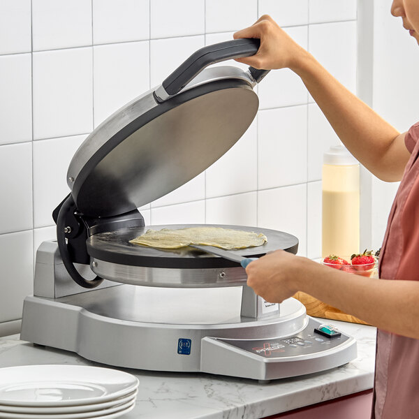 A Waring XPress WSC300 dual-surface aluminum non-stick electric cooktop being used to make a crepe.