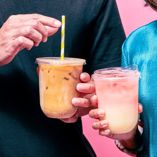 Two people holding Tossware Natural plastic cups with drinks.