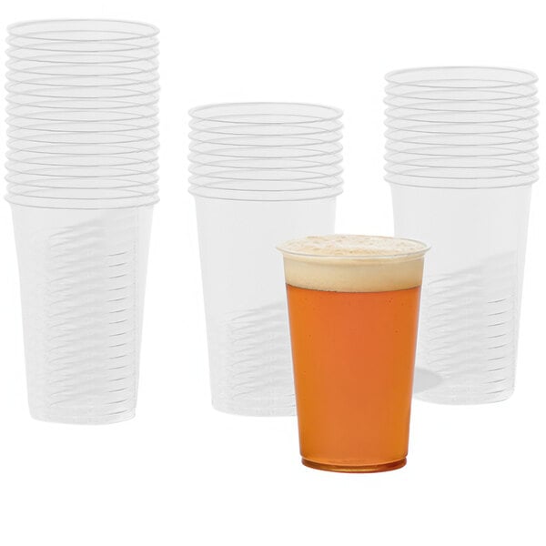 A Tossware plastic cup with a drink in it next to several other plastic cups.