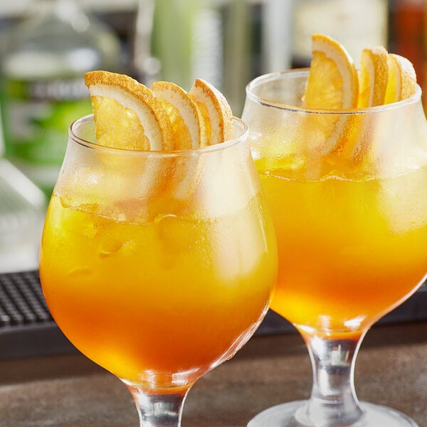 A close-up of two glasses of orange juice with Mixologist's Garden freeze-dried orange slices.